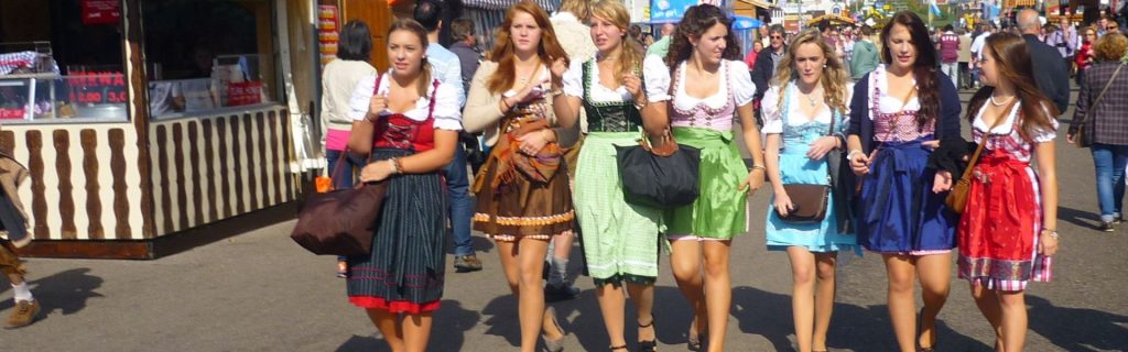 7 junge Frauen laufen fröhlich und vergnügt über das Oktoberfest